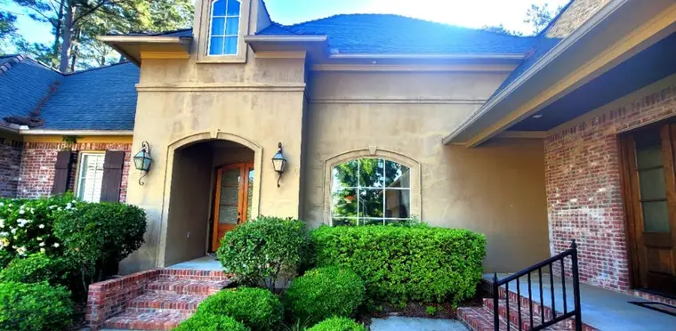 Arched stucco entry beside red brick, before painting
