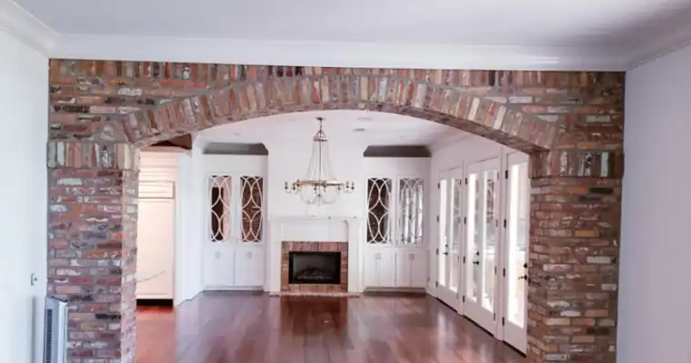 Living room seen through a brick arch, walls and built-ins repainted white