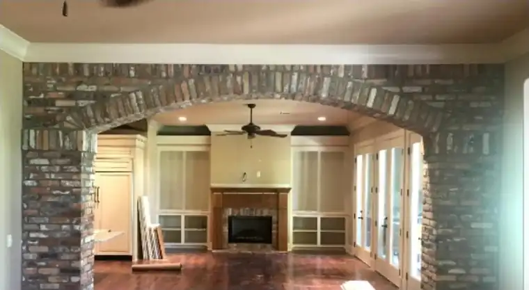 Living room with a brick arch, walls and built-ins repainted white, before painting