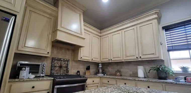 Kitchen with stained cabinets and range hood, before painting