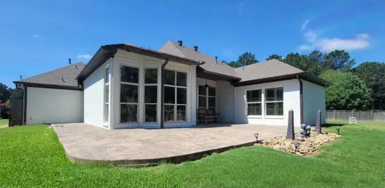 Back of a painted house with a clean stamped-concrete patio and green lawn