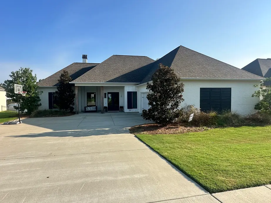 Finished white brick home with dark trim and a wide drive