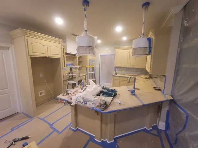 Kitchen mid-job with floors and island masked off and walls prepped for paint